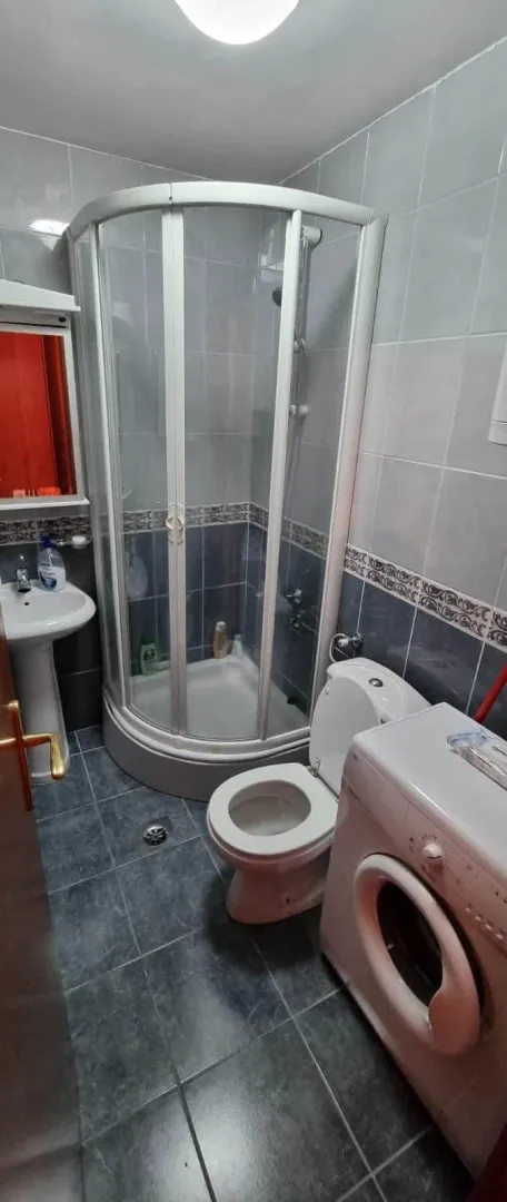 Smaller bathroom with a shower cabin, washbasin, toilet, and washing machine.