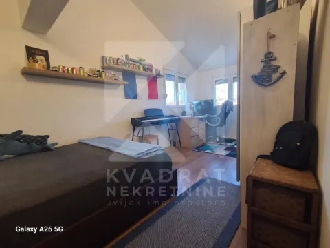 Namještena spavaća soba sa krevetom, radnim stolom i policama na zidu. - image 16