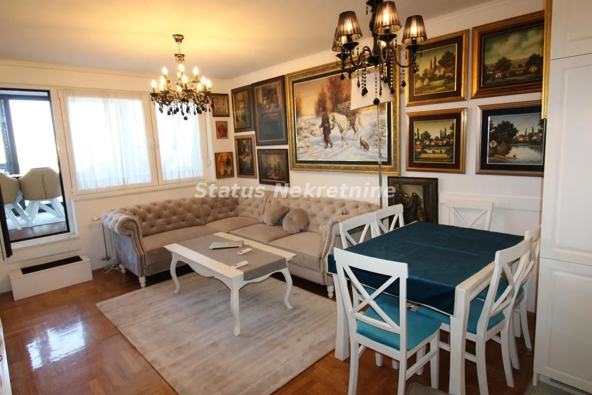 Living room with a sofa set, dining table, and a wall filled with paintings.