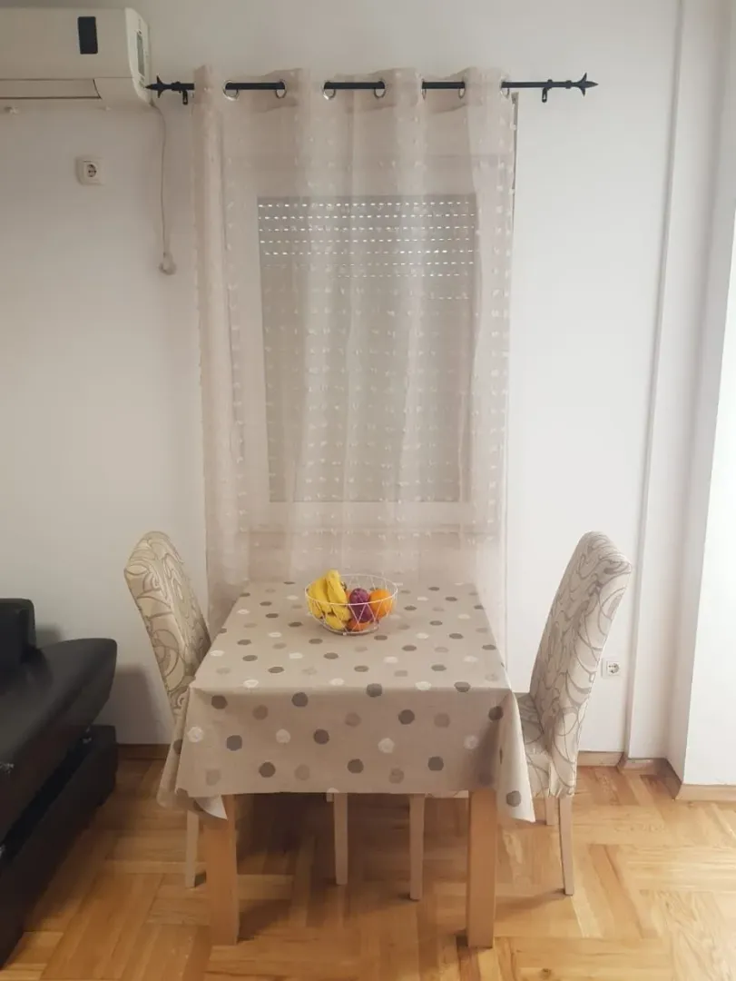 Manji trpezarijski sto sa dvije stolice i prozorom u pozadini.