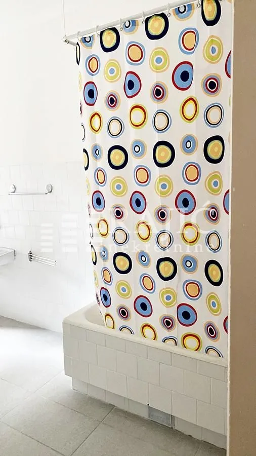 Bathroom with a bathtub and a colorful shower curtain.