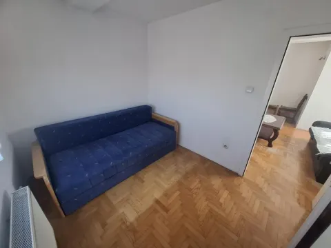 Manja soba sa plavim kaučem i parketom na podu. - image 9