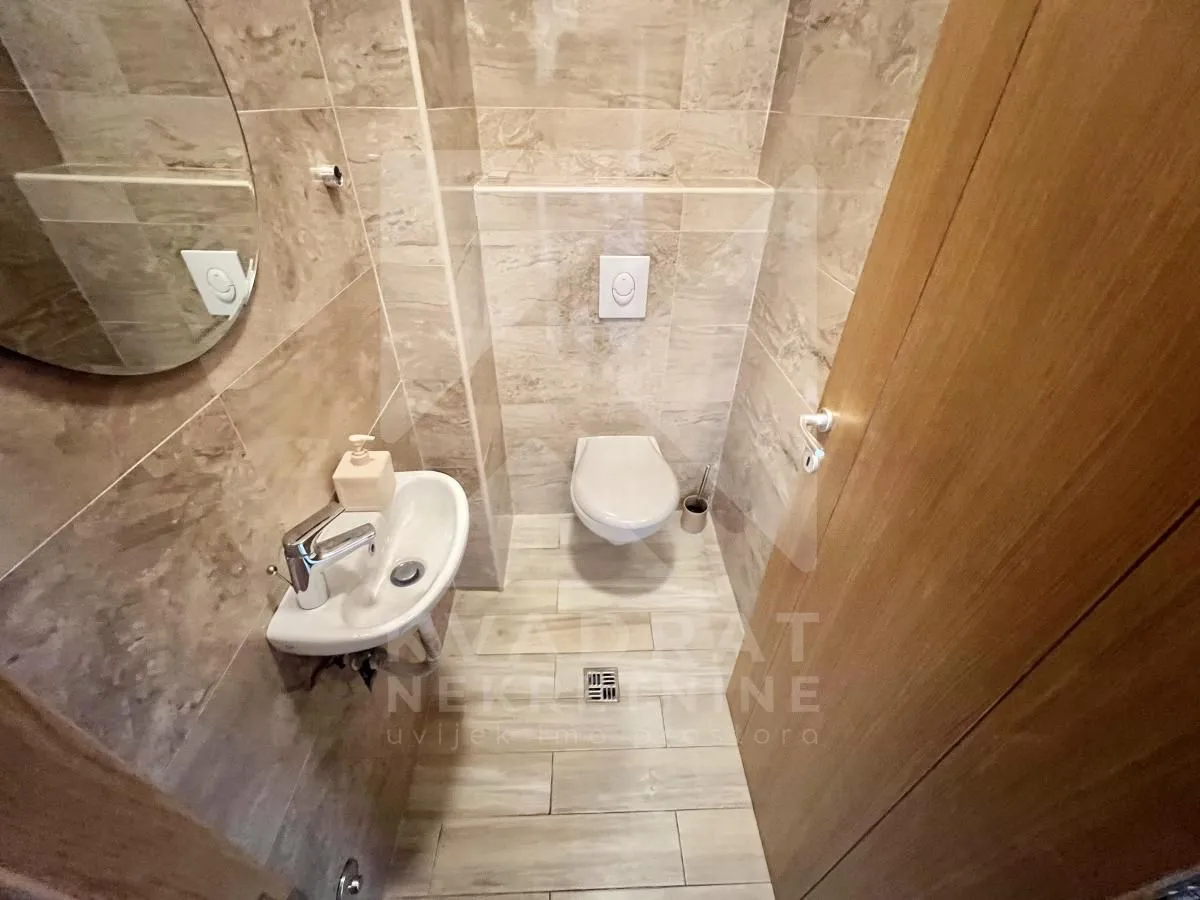 Small tiled bathroom with a washbasin, toilet, and mirror.