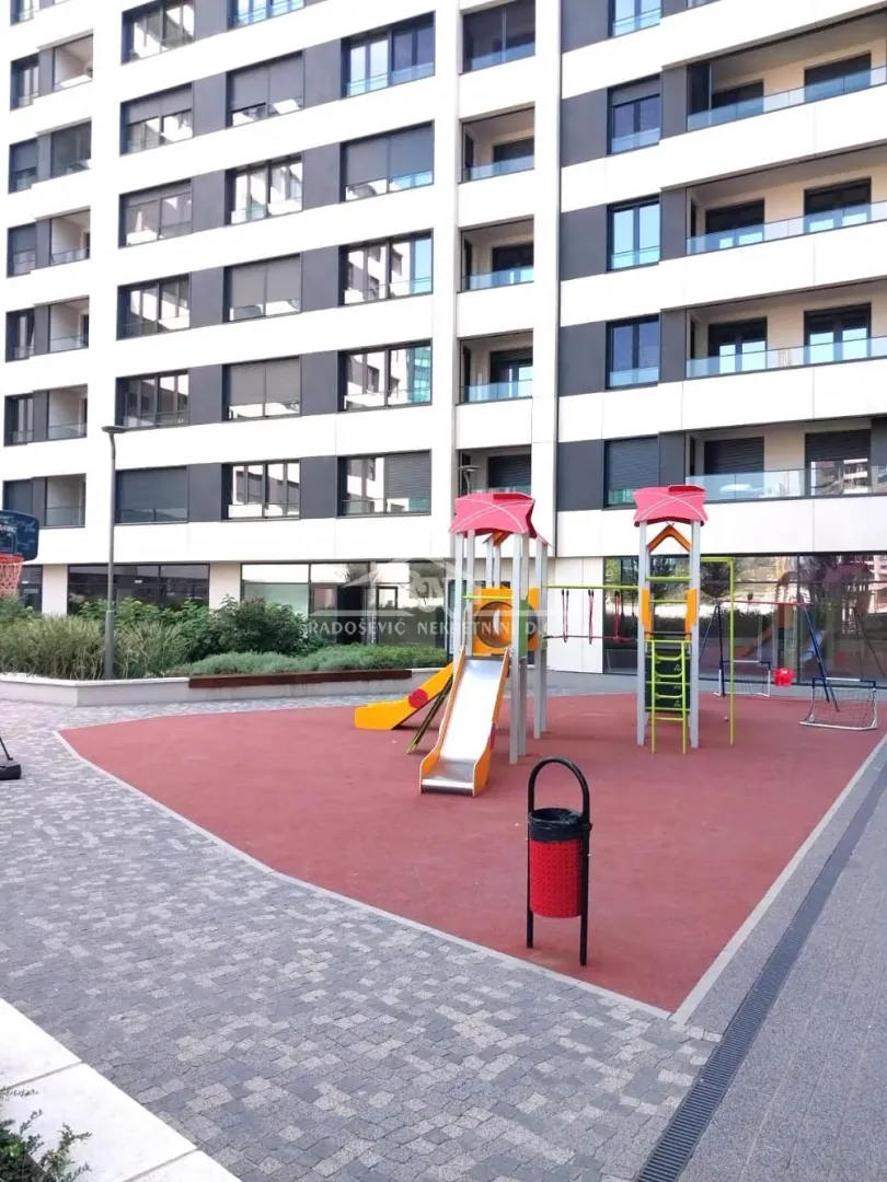 Dečije igralište ispred moderne stambene zgrade.