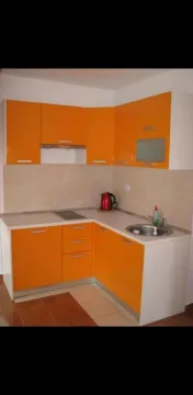 Small kitchen with orange cabinets and white countertops. - image 3