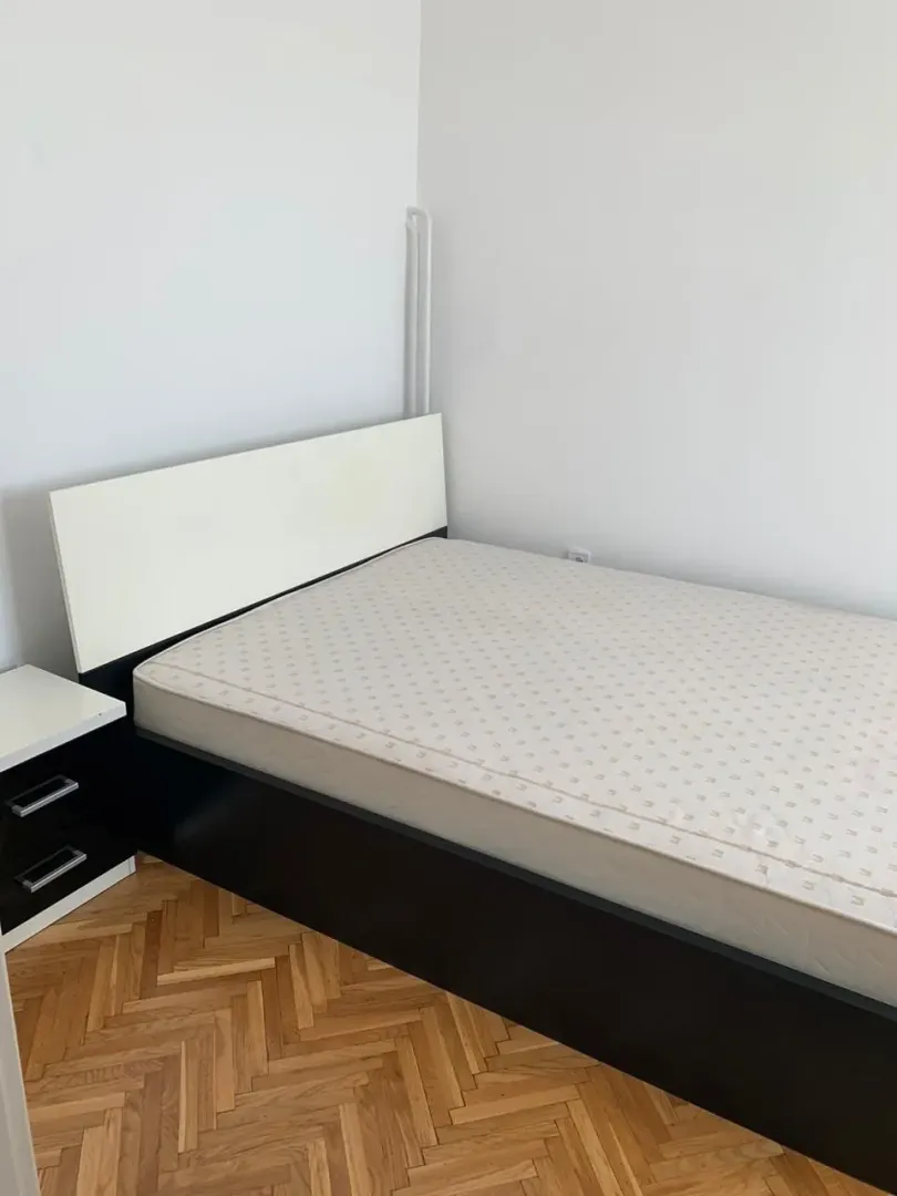 A simple bedroom featuring a bed and a nightstand.