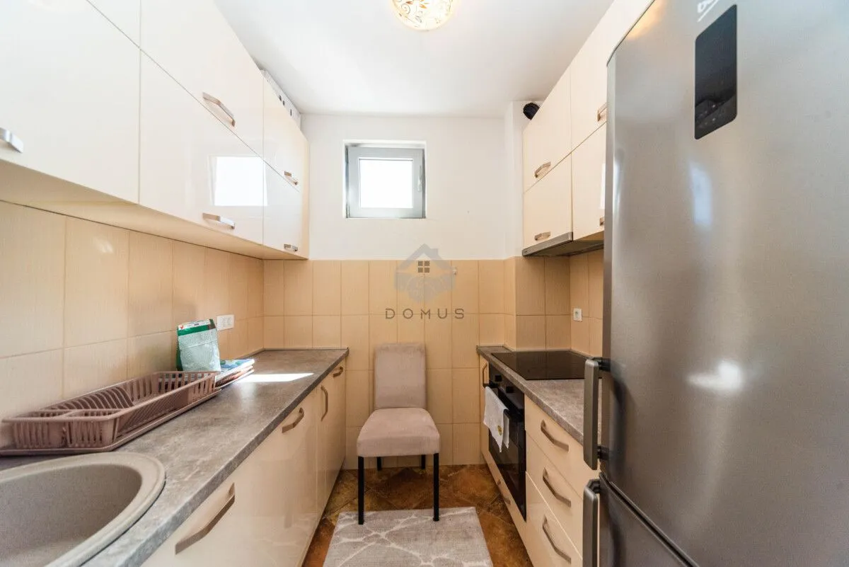 Small kitchen with light cabinetry, built-in appliances, and a refrigerator.