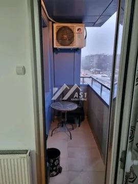 Small covered balcony with a table and air conditioning unit. - image 2