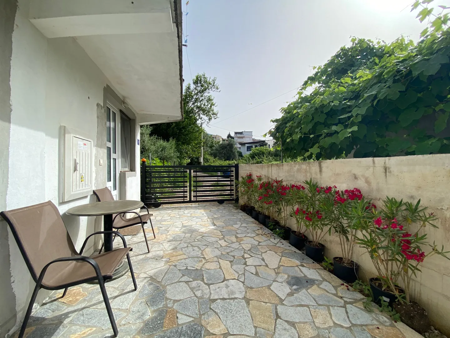 Paved terrace with seating furniture and flowers along the wall.