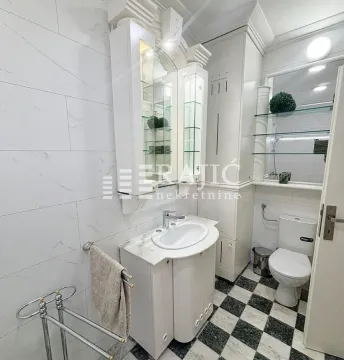 A tidy bathroom with white furniture and black-and-white floor tiles. - image 9