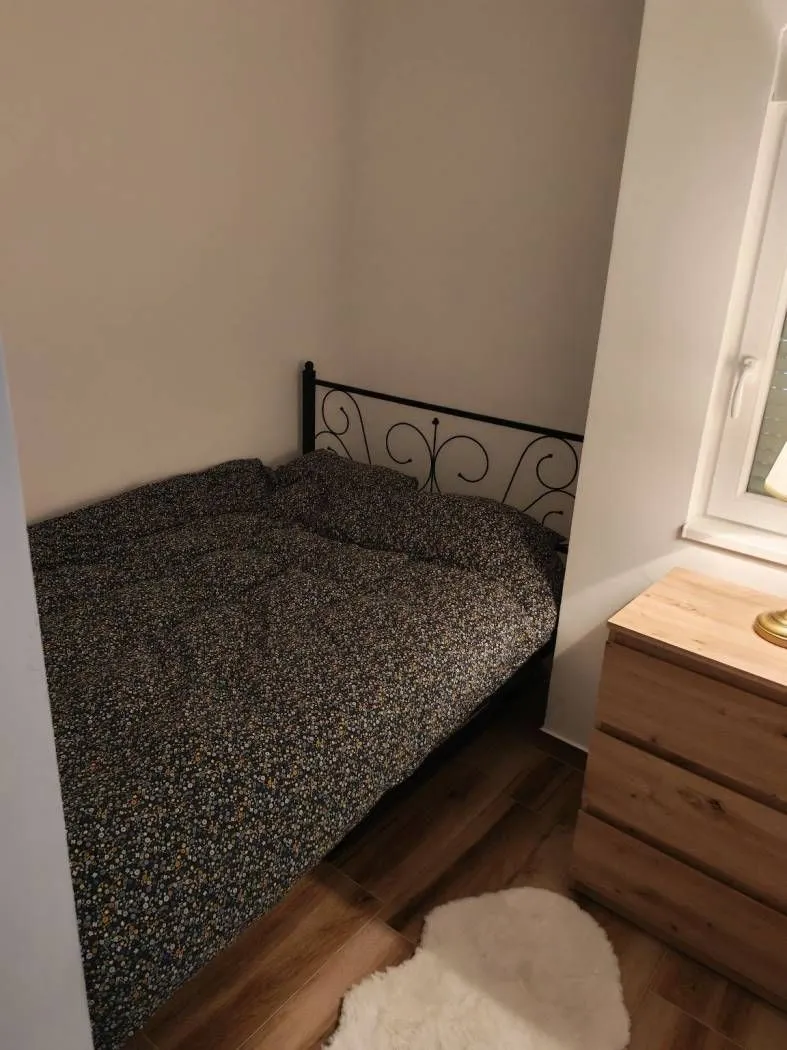 Manja spavaća soba sa bračnim krevetom i komodom.