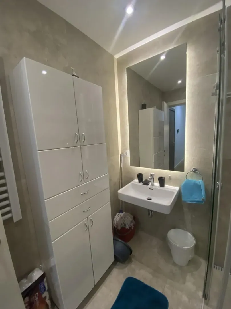 Modern bathroom with a sink, large mirror, and white cabinet.