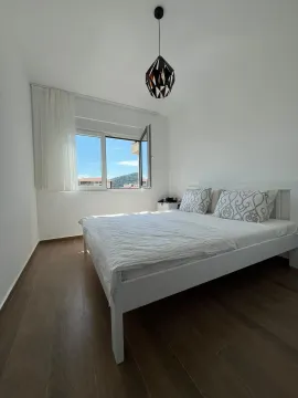 Svjetla i uredna spavaća soba sa bijelim krevetom i prozorom koji gleda na prirodu. - image 6