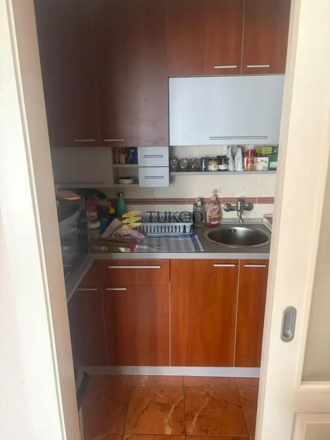 Manja kuhinja sa drvenim elementima i sudoperom.