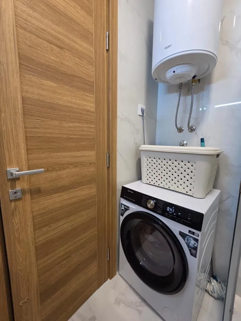 Bathroom with a washing machine, water heater, and wooden doors.