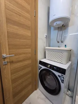 Bathroom with a washing machine, water heater, and wooden doors. - image 22