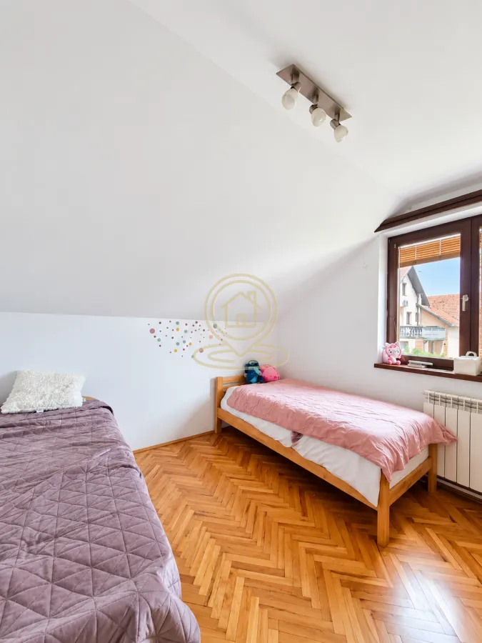 Attic bedroom with two single beds and wooden parquet flooring.