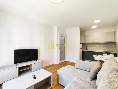 Living room with sofa, TV and kitchen in the background. - image 9