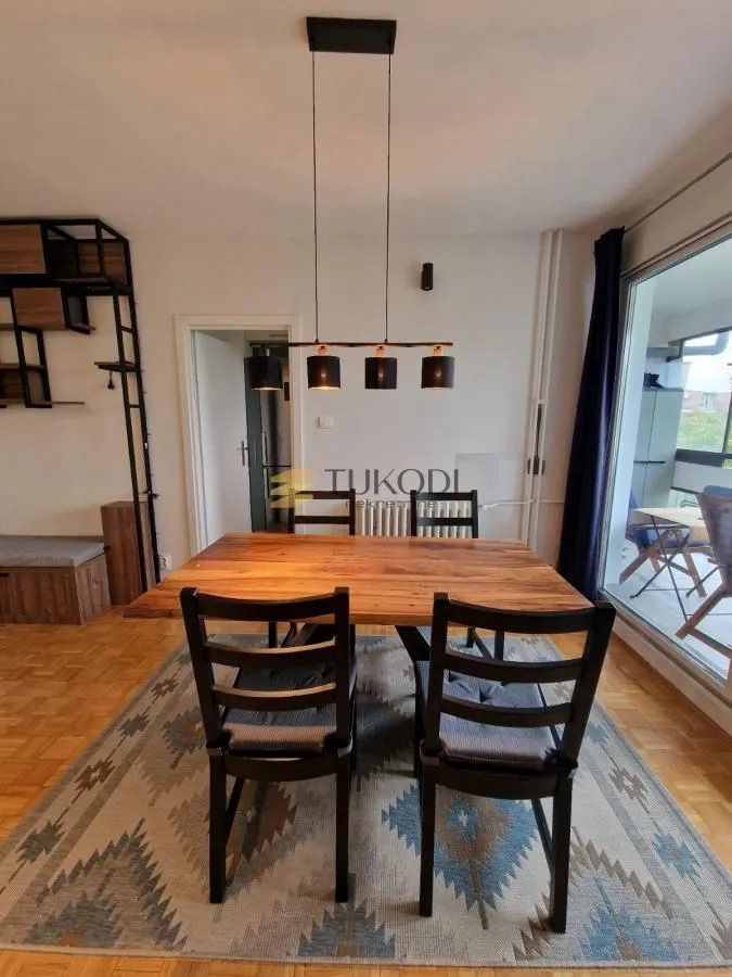 Dining area with a wooden table, black chairs and a pendant light.