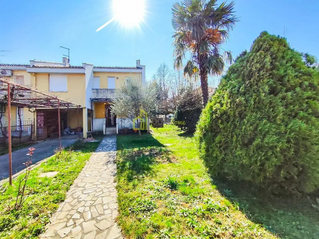 Pogled na dvorište i fasadu kuće sa stazom i zelenilom.