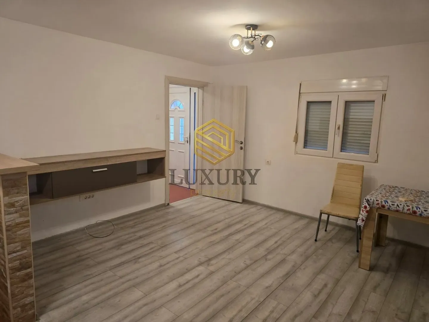 Empty room with laminate flooring, a table and a chair.