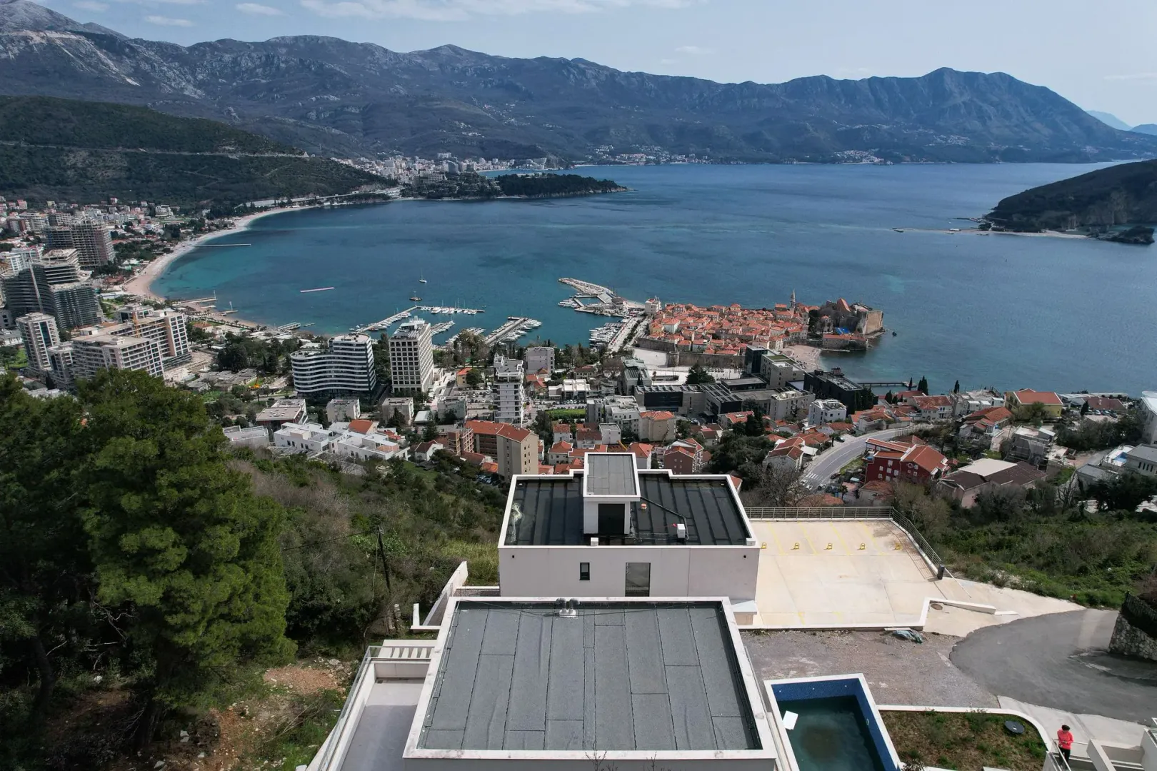 Pogled iz vazduha na grad, marinu i more iznad kojeg se uzdižu planine.