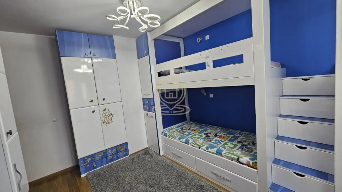 Children's bedroom with a bunk bed, built-in wardrobes, and a rug.