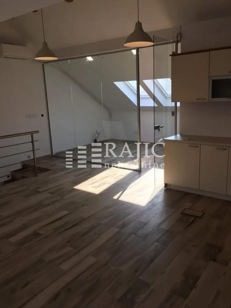 Interior view of a bright living room with wooden flooring and a glass partition.