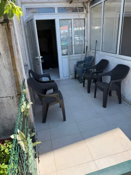 Natkrivena terasa sa plastičnim stolicama i pogledom na ulazna vrata. - image 2