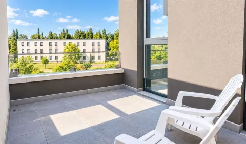 Spacious terrace with a glass railing and white plastic chairs. - image 22