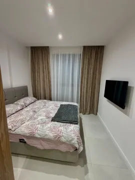Furnished bedroom with a double bed, window, and wall-mounted television. - image 8