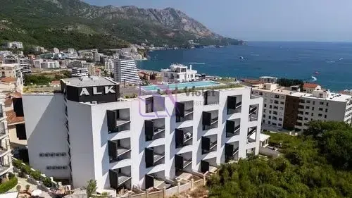 Pogled iz vazduha na hotelski objekat sa bazenom na krovu blizu obale mora.