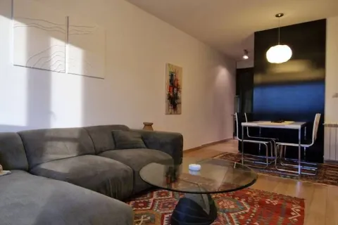 Living room with a sofa, glass coffee table, and a dining area in the background. - image 12