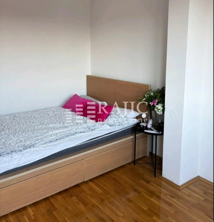 Small bedroom with a bed and wooden flooring.