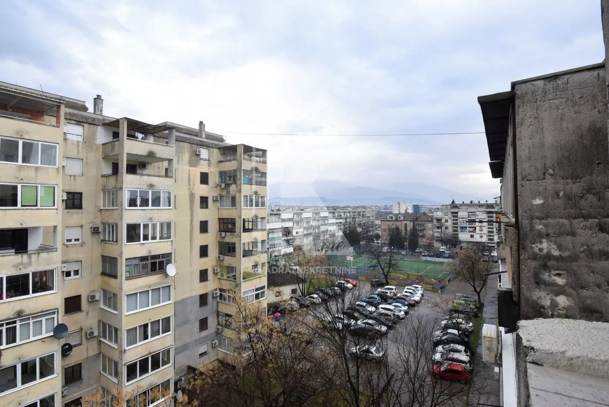 Pogled iz stana na okolne stambene zgrade i parking.