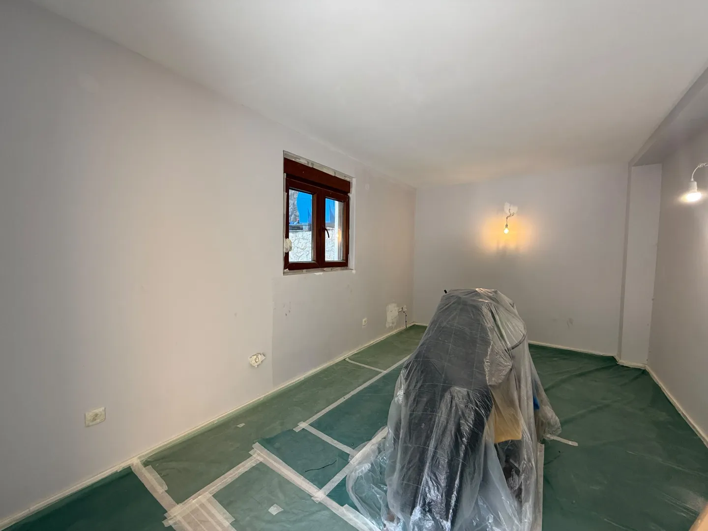 Prazna prostorija u toku renoviranja sa podom prekrivenom zaštitnom folijom.
