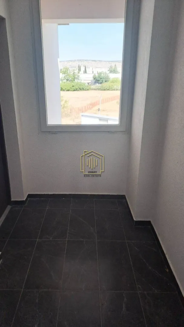 Nenamještena terasa sa prozorom i pogledom na prirodu.