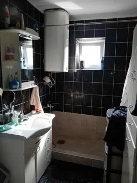 Manje kupatilo sa tuš kabinom i crnim zidnim pločicama. - image 17