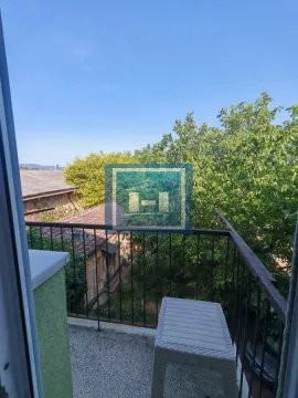 Manji balkon sa metalnom ogradom i pogledom na zelenilo i okolne objekte. - image 13