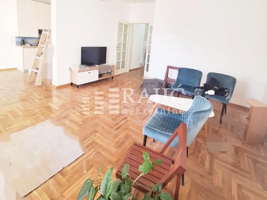 Living room with parquet flooring and blue chairs.