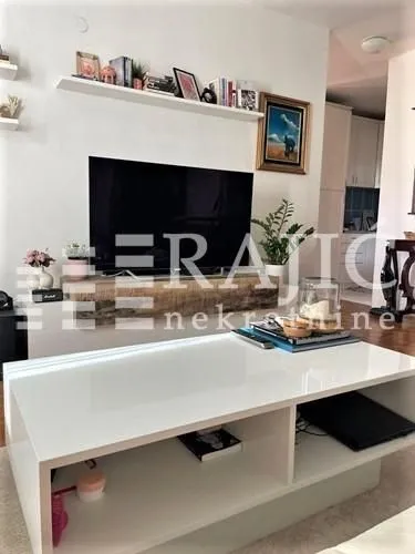 Living room with a television, shelving unit, and a white coffee table.