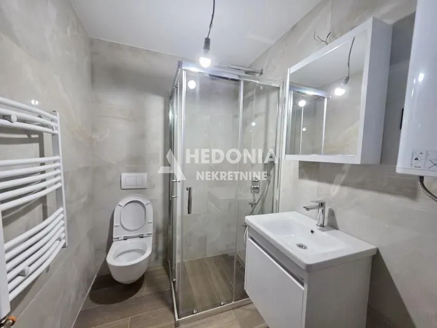 Moderno opremljeno kupatilo sa tuš kabinom, umivaonikom i WC šoljom.
