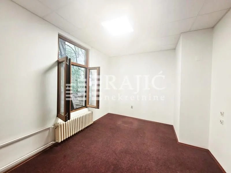 Empty office room with a window and a radiator.