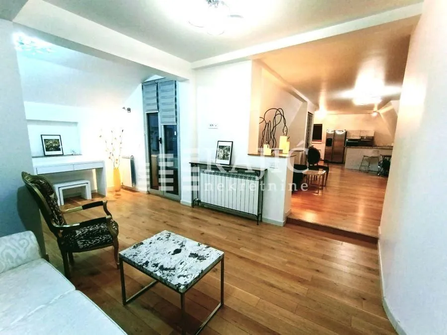 Spacious living room with wooden flooring and a view of the kitchen.