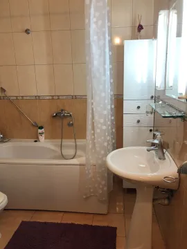 A simple bathroom featuring a bathtub, pedestal sink, and white cabinet. - image 18