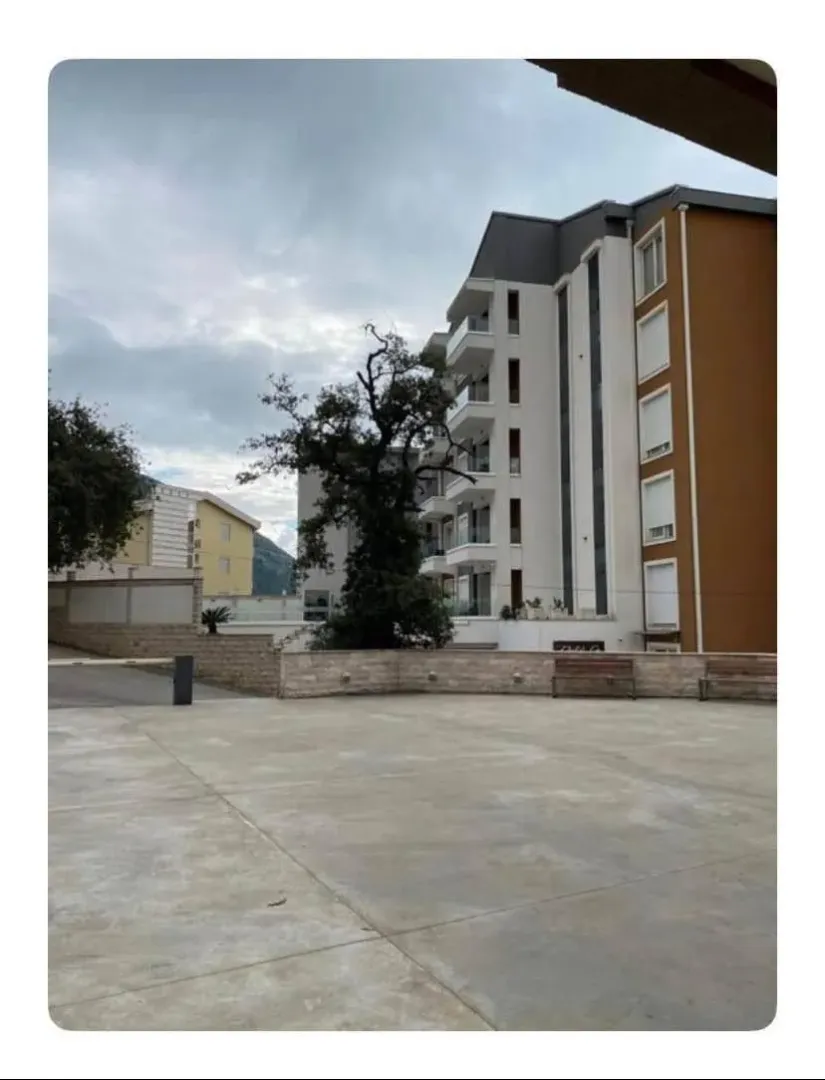 Eksterijer stambene zgrade sa popločanim dvorištem.