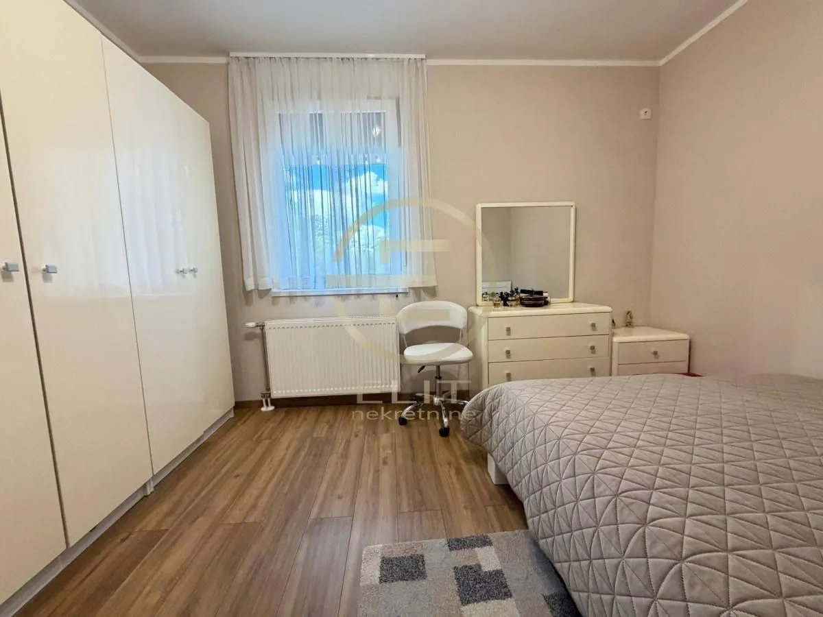 Nameštena spavaća soba sa velikim garderoberom, bračnim krevetom i komodom sa ogledalom.