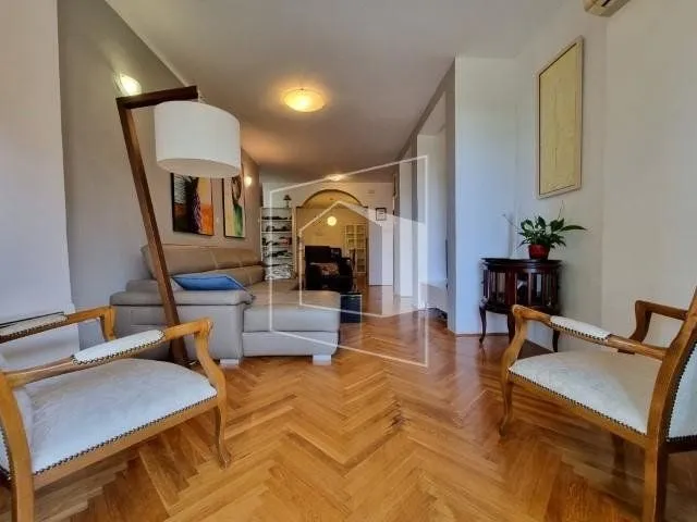 Spacious living room with a sofa and parquet flooring.