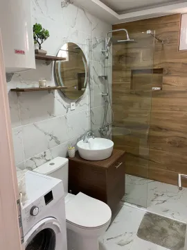 Modern bathroom with a walk-in shower, washbasin, washing machine, and white ceramic tiles. - image 13