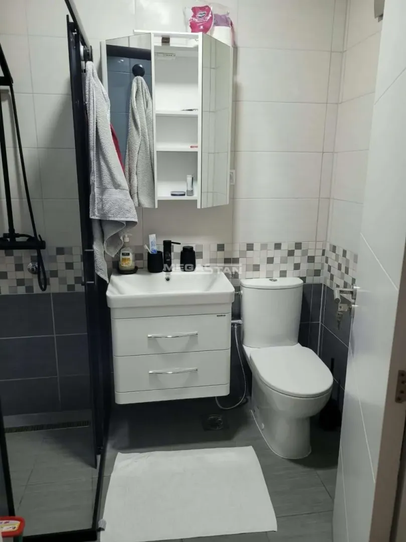 Kupatilo opremljeno umivaonikom, WC šoljom i tuš kabinom.
